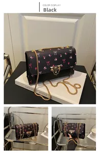 Detail of black chain shoulder bag with pink floral patterns and gold vintage lock