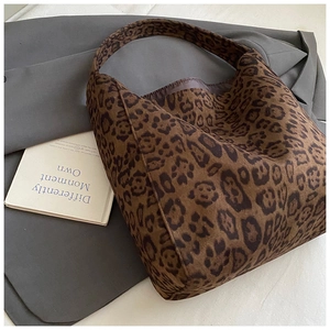 Detail of leopard print tote bag with soft suede texture on a grey blazer backdrop