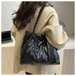 Detail of black tote bag with quilted diagonal texture and woven shoulder strap
