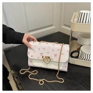 Detail of white floral crossbody bag with pink bow prints and gold chain strap