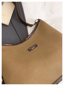Close-up of canvas bucket bag detailing premium leather trim and branded logo patch