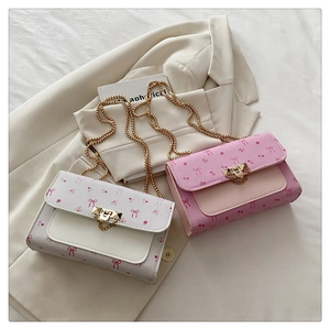 Detail of pink and white crossbody bags with floral bow prints and gold chain straps