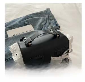 Dettaglio borsa retrò in pelle nera con bordo in pizzo bianco e decorazione con fiocco