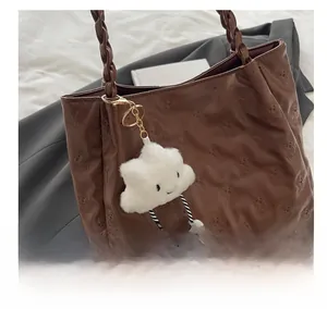 Close-up of brown tote bag featuring 3D teddy bear embossing and woven handle detail