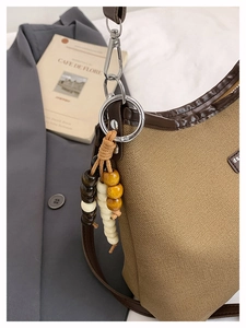 Detail of canvas bucket bag with brown leather trim and retro wooden bead tassel charm