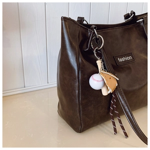 Détail d'un cabas marron foncé avec étiquette fashion et accessoire de porte-clé baseball