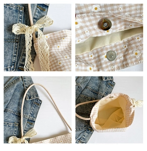 Detail view of daisy print canvas bag with lace bow, magnetic clasp and checkered fabric