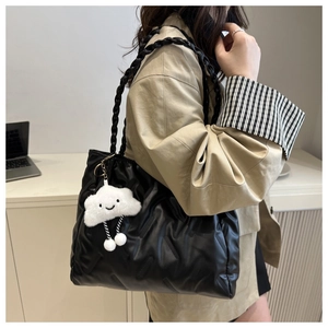Detail of black pleated tote bag with diamond texture and white cloud plush pendant