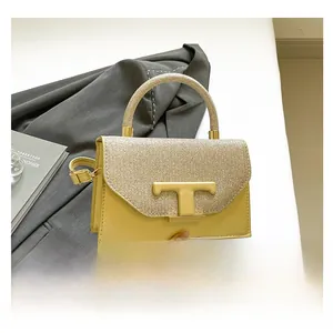 Detail of yellow crossbody bag featuring golden T-shaped buckle and glitter texture flap
