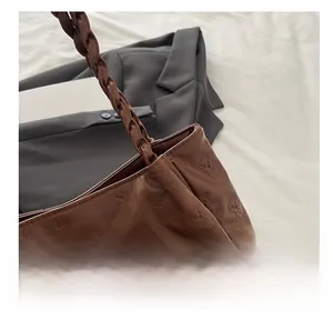 Detail of brown leather tote with embossed bear pattern and braided shoulder strap