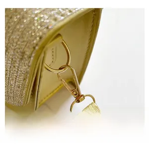 Macro view of ginger yellow crossbody bag showing gold metal hardware and textured strap
