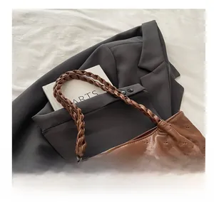 Detail of brown tote bag with quilted heart texture and woven handle with white puff ball