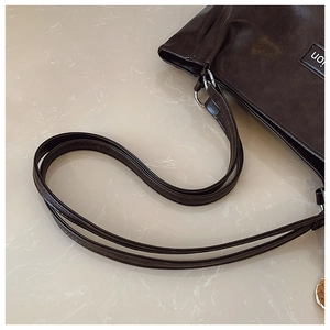 Détail d'un sac cabas en cuir marron foncé avec finition mate et anneaux en métal argenté