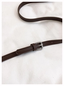 Close-up of adjustable dark brown leather strap with silver buckle and fine edge stitching