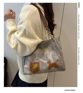 Détail du sac cabas en toile grise avec bandoulière en similicuir brun et boucles d'or
