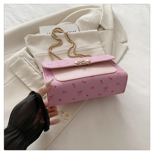 Détail du sac bandoulière rose à fleurs avec chaîne dorée sur un blazer beige