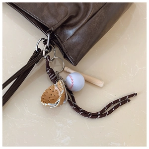 Porte-clés baseball avec batte en bois et gant sur un sac cabas marron élégant