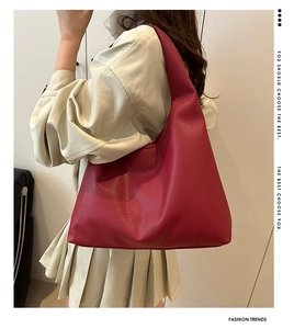 Side view of red pebble leather tote bag worn over the shoulder by a model