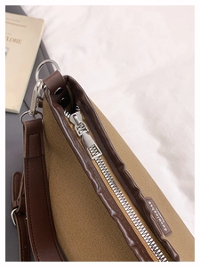 Close-up of canvas and leather stitching with metal zipper on a large tote bag