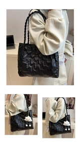 Detail of black quilted tote bag with bear patterns, woven handles and cloud charm