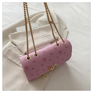 Détail du sac à fleurs rose avec chaîne dorée sur un blazer blanc en arrière-plan