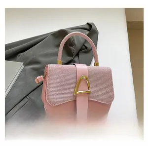Détail d'un sac à main rose pailleté avec un fermoir en métal géométrique doré chic