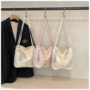 Detailed embroidery on satin handbags in gold, pink, and white with elegant silk tassels