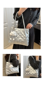 Detail of silver metallic tote bag featuring quilted texture and cute cloud plush charm