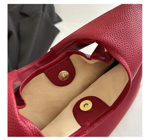 Detail of red lychee grain leather tote bag featuring a secure golden magnetic buckle closure