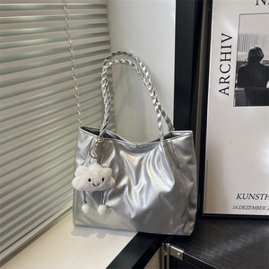 Silver metallic tote bag with woven handles and a cute cloud charm on a white surface