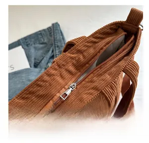 Detail view of smooth silver metal zipper and brown corduroy fabric texture on tote bag