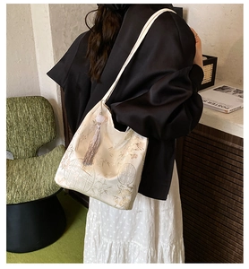 Detail of white silk tote bag with traditional Chinese floral embroidery and tassel charm