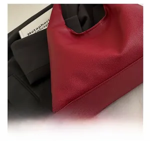 Detail of red litchi texture handbag showing precise stitching and premium leather finish