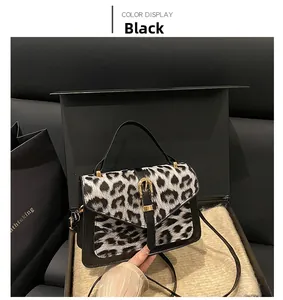 Detail of leopard print flap and golden buckle on elegant black leather handbag