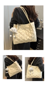 Detail of cream quilted tote bag featuring bear embroidery and plush cloud charm accessory