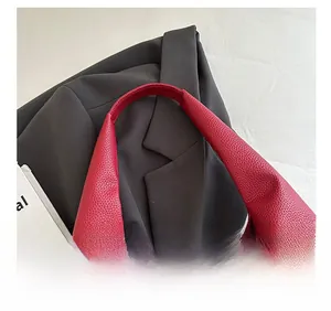 Detailed close-up of comfortable shoulder strap on red lychee pattern leather tote bag