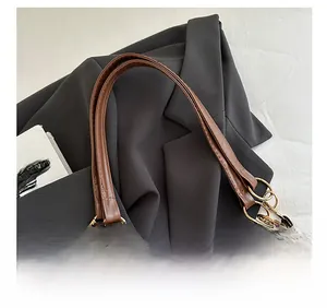 Détail du cabas en tissu gris avec anses en cuir marron et anneaux de liaison dorés en métal