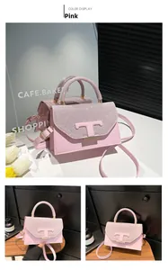 Detail of pink small square bag featuring sparkling glitter flap and iconic T-shaped metal clasp