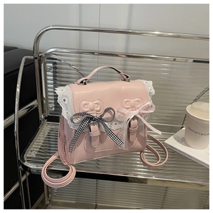Dettaglio di zaino in pelle PU rosa con bordi in pizzo e fiocchi su sedia in metallo