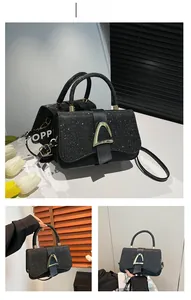 Détail du sac bandoulière à paillettes noires avec boucle dorée et poignée anneau