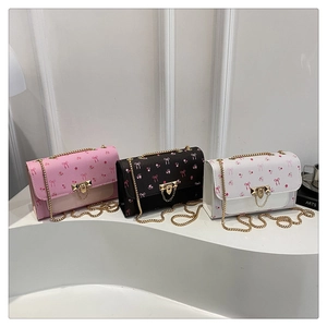 Three cherry print crossbody bags in pink, black and white with metal chain straps