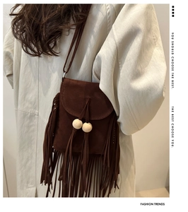 Détail d'un sac bandoulière en suédine marron foncé avec de longues franges et perles