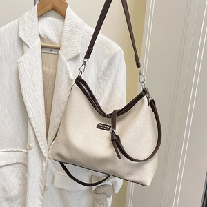Minimalist canvas bucket bag with brown leather trim shown on a stylish hanger