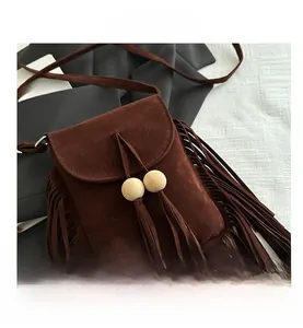 Détail du sac bandoulière en daim marron avec franges bohèmes et perles en bois