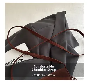 Détail de la bandoulière en daim marron avec coutures précises sur un sac rétro chic