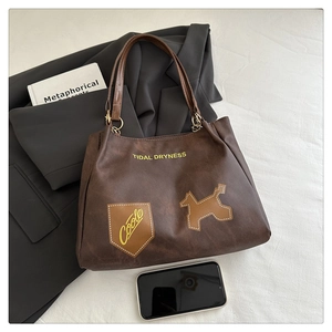Détail du sac cabas marron foncé avec lettrage jaune et texture rétro élégante