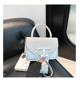 Detail of silver sequined handbag featuring a metallic T-shaped clasp and silk texture
