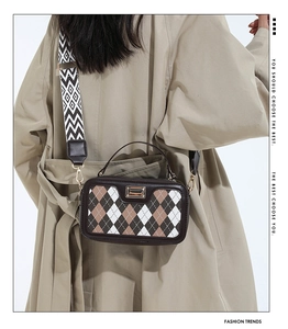 Detail of color-block plaid crossbody bag with wide strap on khaki trench coat