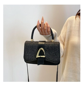 Détail du sac à main noir pailleté avec boucle fer à cheval dorée et fine bandoulière