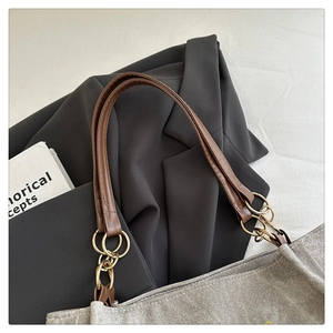 Détails du sac fourre-tout gris texturé avec poignée en cuir marron et anneaux dorés